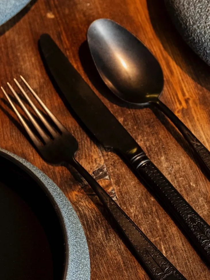 Matte black cutlery on a timber table